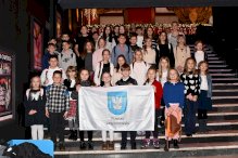 Zdjęcie grupowe uczestników wyjazdu do teatru.Uczniowie trzymają flagę Powiatu Legionowskiego