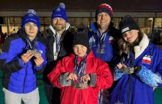 Na zdjęciu widać dwóch mężczyzn, jednego młodego chłopca i dwie dziewczynki, wszyscy ubrani w zimowe niebieskie bądź czerwone stroje z medalami na szyjach