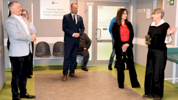 Na zdjęciu widać w całej postaci dwóch mężczyzn i stojące obok trzy kobiety, razem zwiedzają legionowską przychodnię