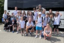 Grupa zawodników UKP „Ósemka" Legionowo z trenerami przed wyjazdem na zawody w tle autobus.