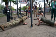 Zawodnicy ćwiczący pompki i przysiady na terenie street workout