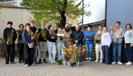 Powiększ obraz: Na zdjęciu uczniowie i przedstawiciele Powiatu z roślinami i akcesoriami na tle szkoły
