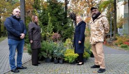 Powiększ obraz: Na zdjęciu przedstawiciele Powiatu i DPS Kombatant z roślinami i akcesoriami na tle ogrodu