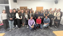 Powiększ obraz: Wspólne zdjęcie uczestników szkolenia „Szkoła Turystyki Zrównoważonej”. Grupa kilkudziesięciu osób stoi i siedzi w sali konferencyjnej, uśmiechając się do obiektywu. Wśród uczestników są zarówno młodzież, jak i dorośli – przedstawiciele różnych środowisk zaangażowanych w rozwój turystyki.