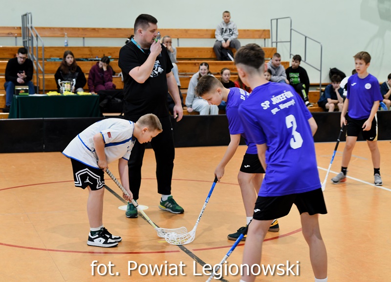 Na zdjęciu rywalizujący na boisku chłopcy grający w unihokeja